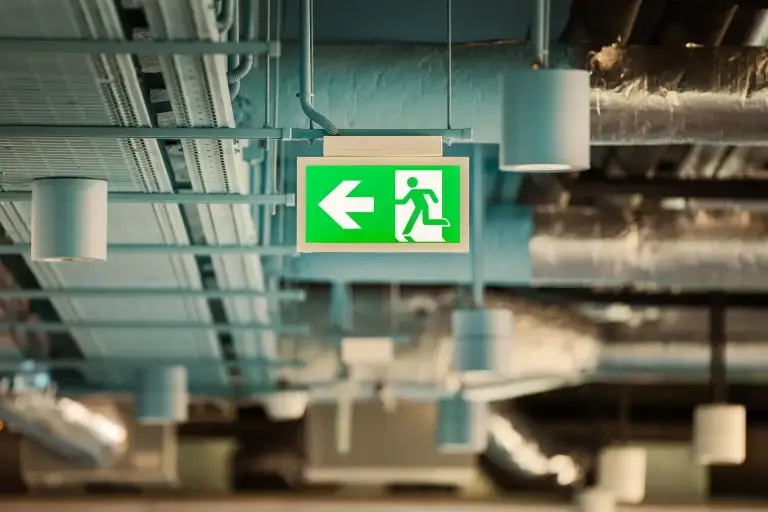 Illuminated green emergency exit sign on a Sydney commercial building ceiling