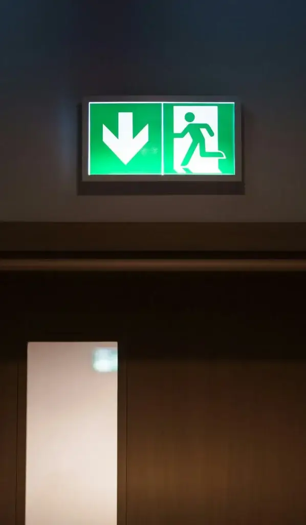 Illuminated running man exit sign above a doorway in a Sydney building