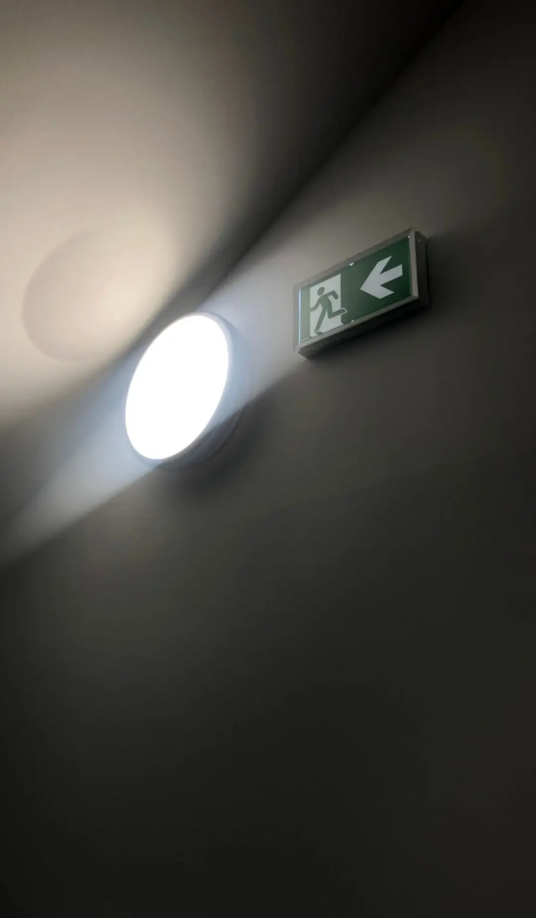 Illuminated emergency light beside an exit sign on a wall in a Sydney building