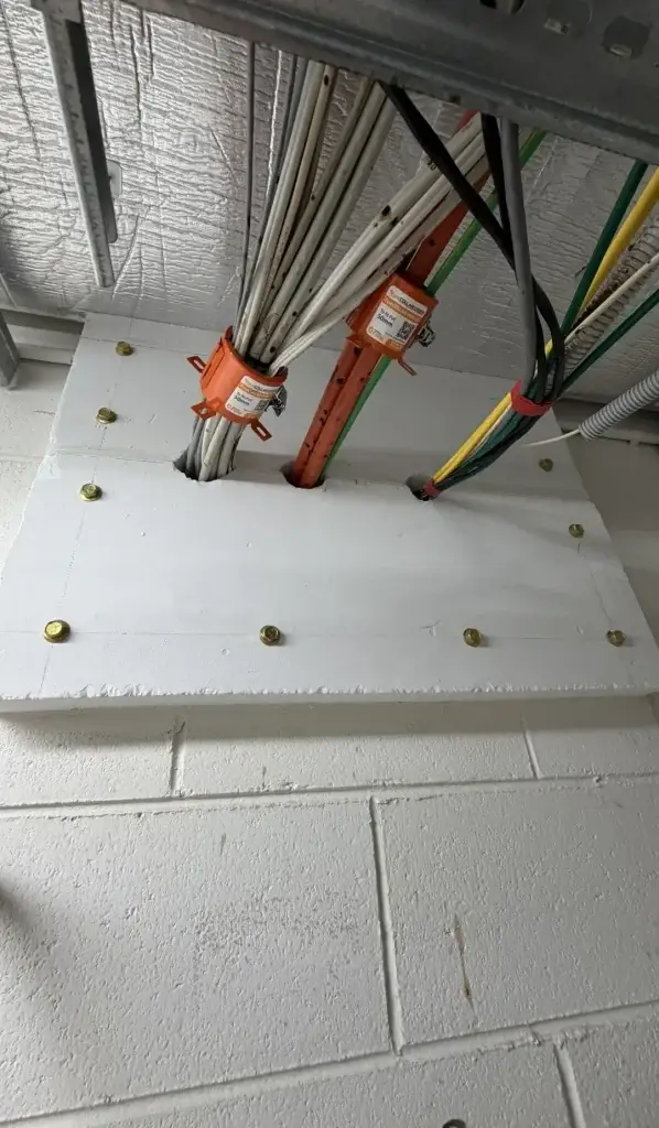Fire-rated sleeves and collars sealing cable penetrations through a fire-rated floor
