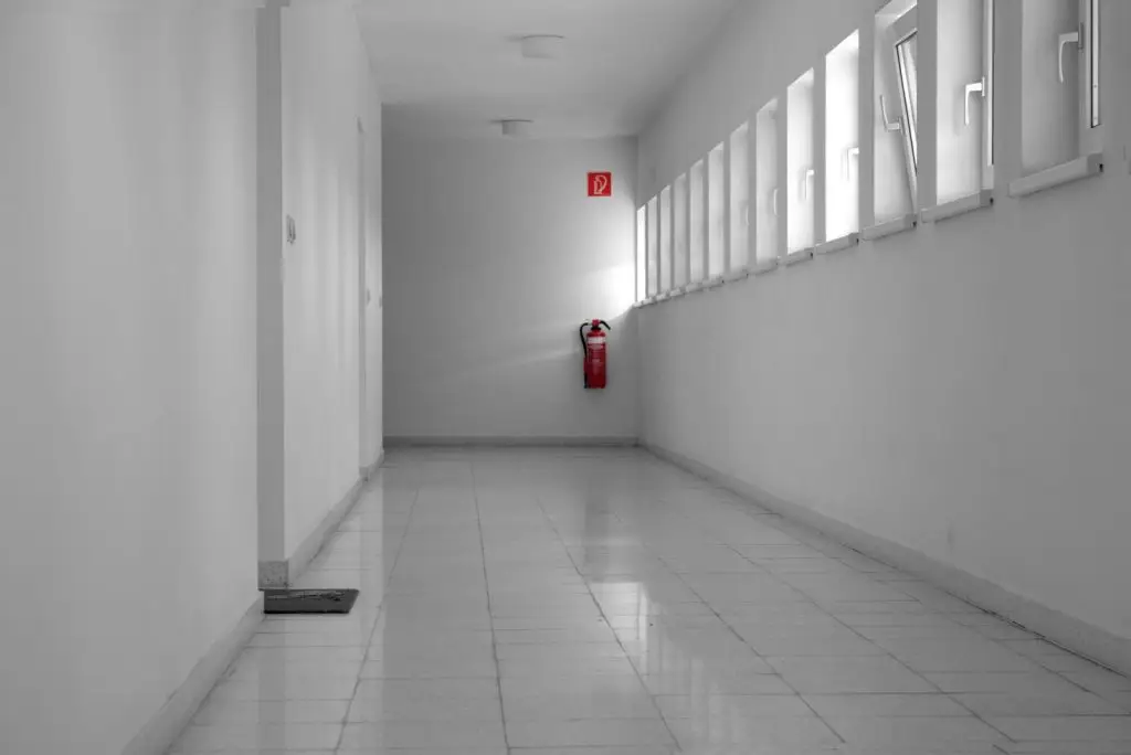 Fire extinguisher mounted on a corridor wall along an exit path