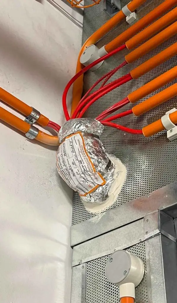 Fire-rated wrap sealing a cable bundle where it passes through a fire barrier wall