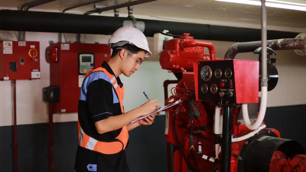 Fire technician recording inspection results in a building pump room